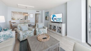 Ein modernes Wohnzimmer mit Essbereich, einem Fernsehgerät an der Wand und Blick auf den Ozean.