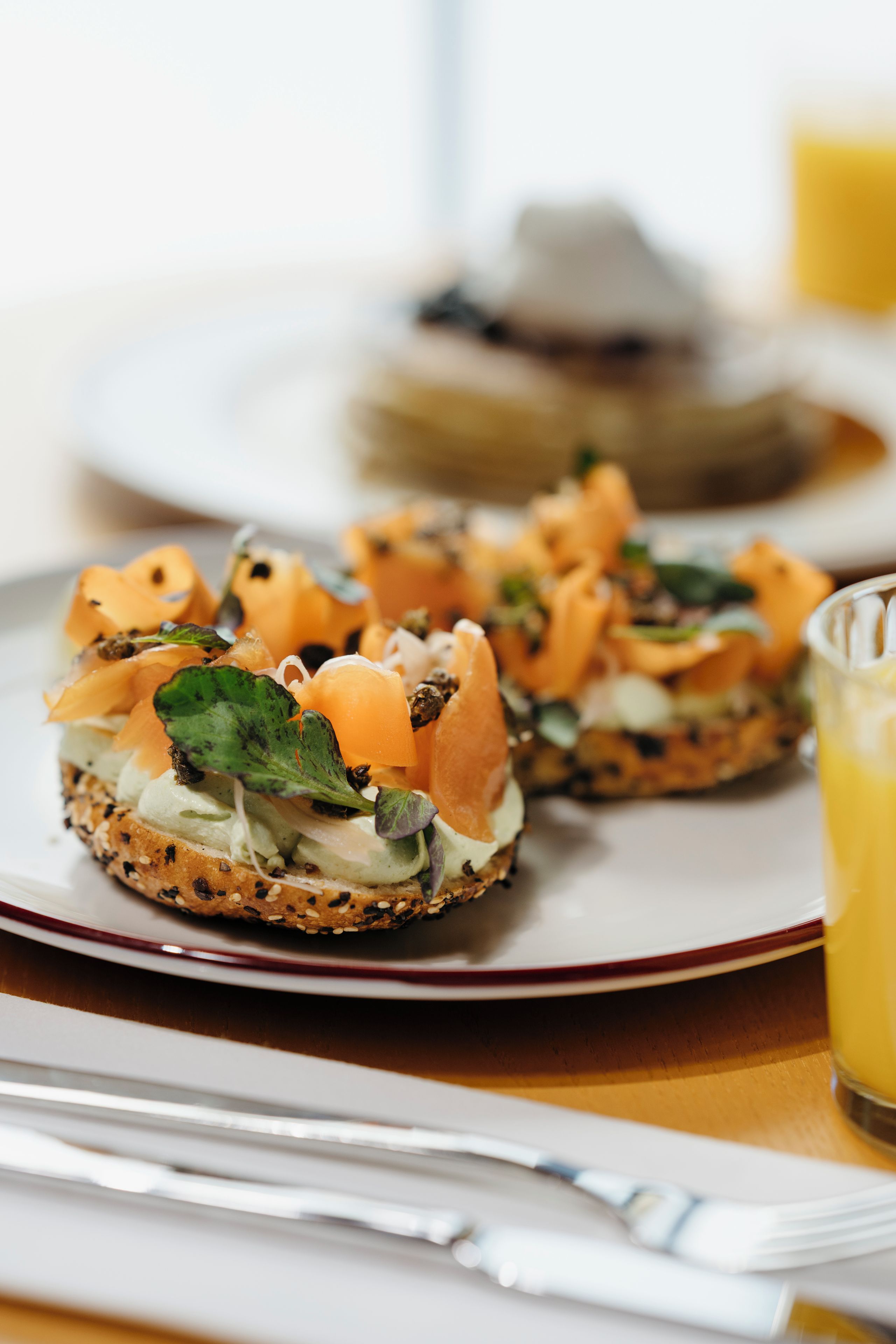 Plat de menjar amb diferents ingredients, com formatge crema, salmó fumat i verdures, presentat sobre un bagel integral.
