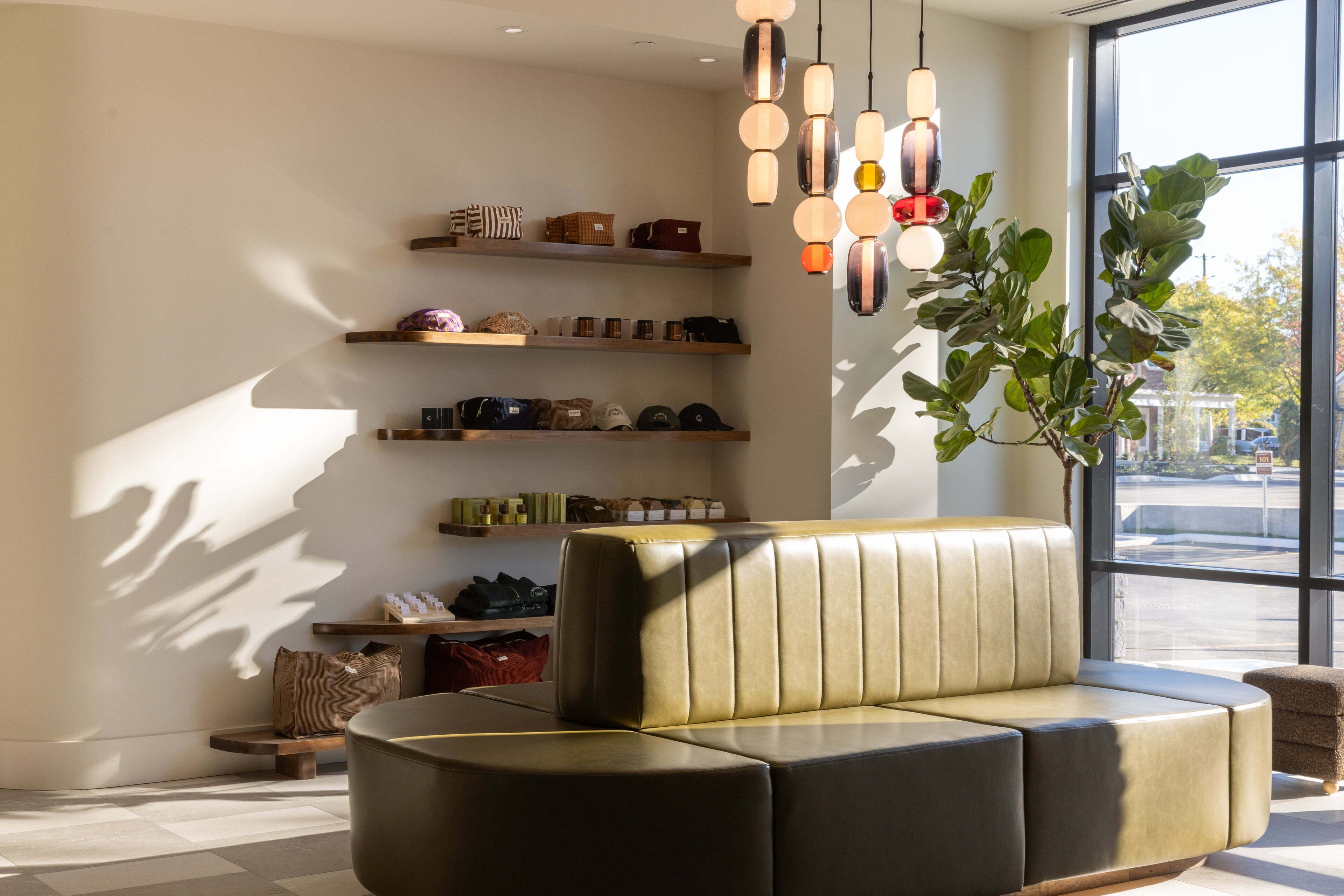 Un intérieur moderne avec un canapé en cuir, des étagères remplies de sacs et des lampes suspendues.