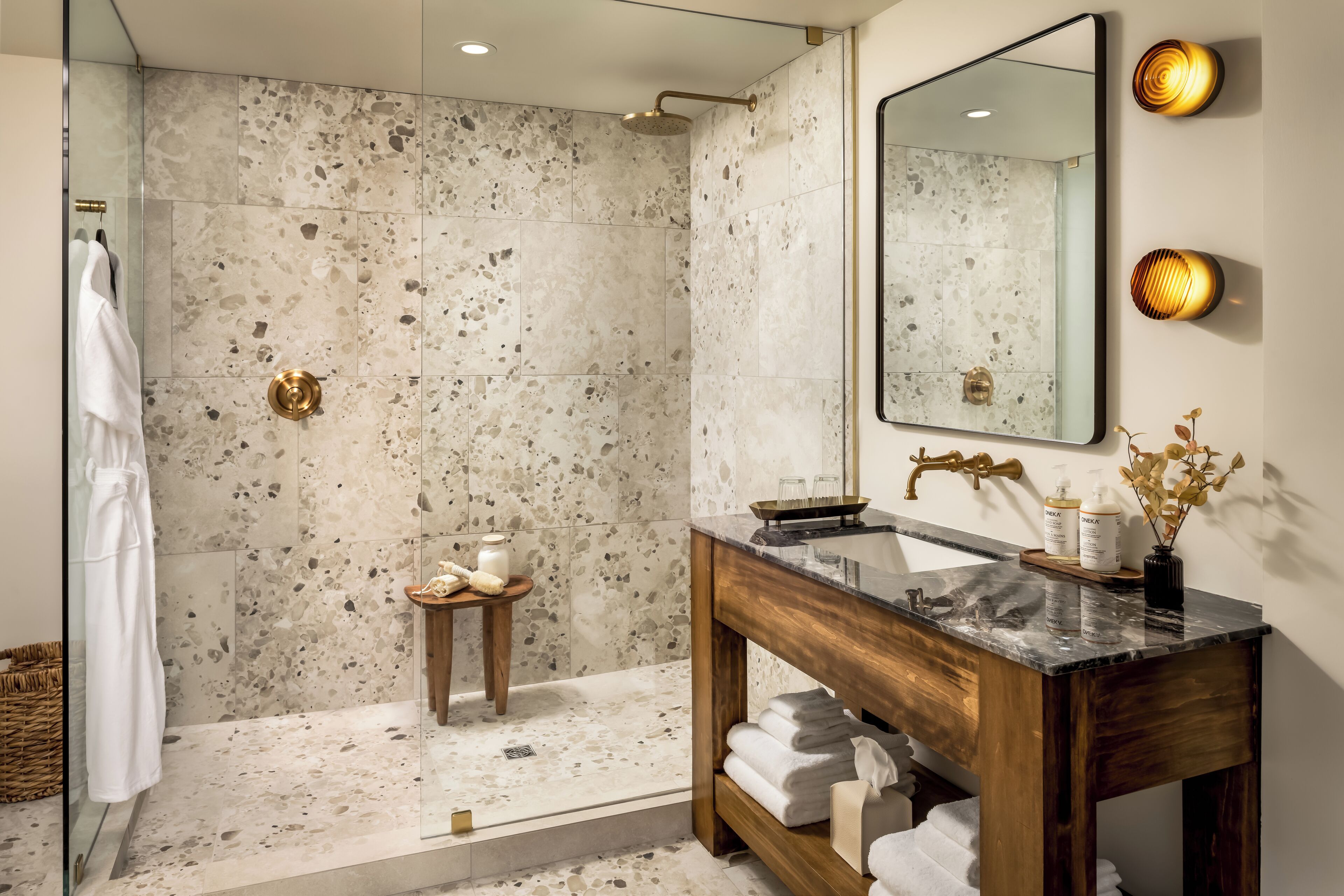 A modern bathroom with a shower, a vanity with a marble countertop, and a large mirror.