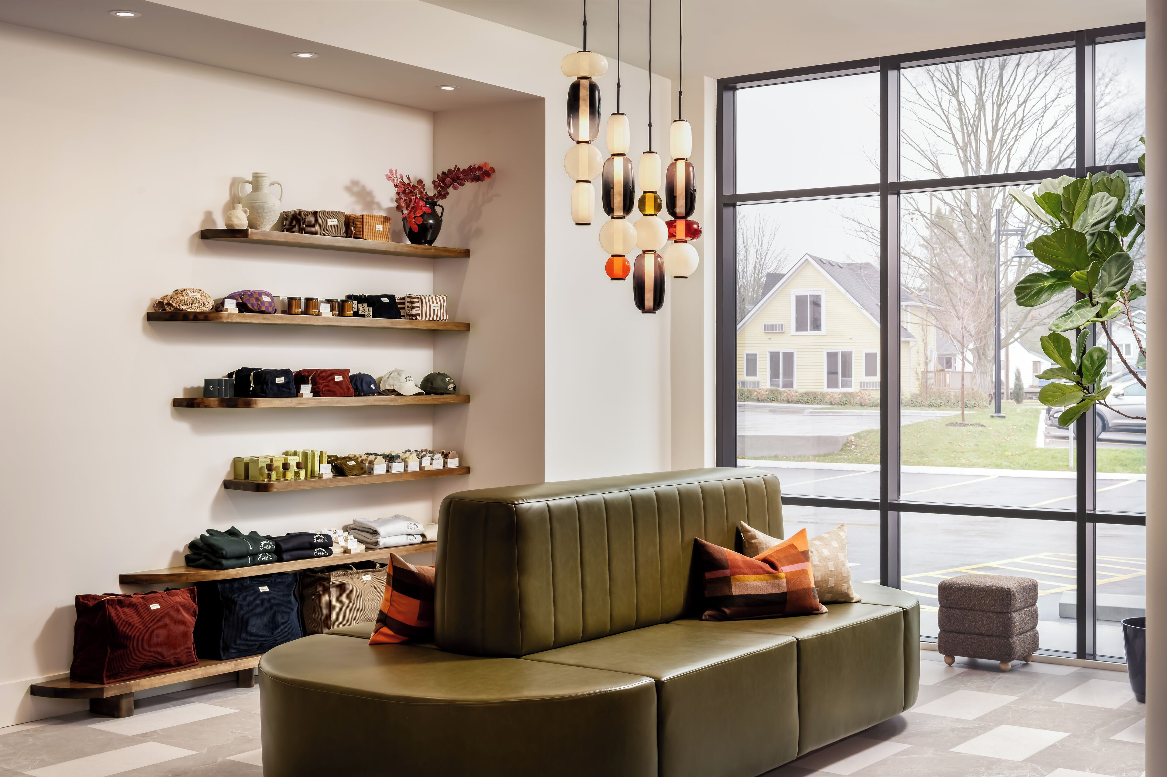 Ein modernes Wohnzimmer mit einem grünen Sofa, mehreren Regalen mit verschiedenen Gegenständen und einem großen Fenster mit Blick auf Häuser.