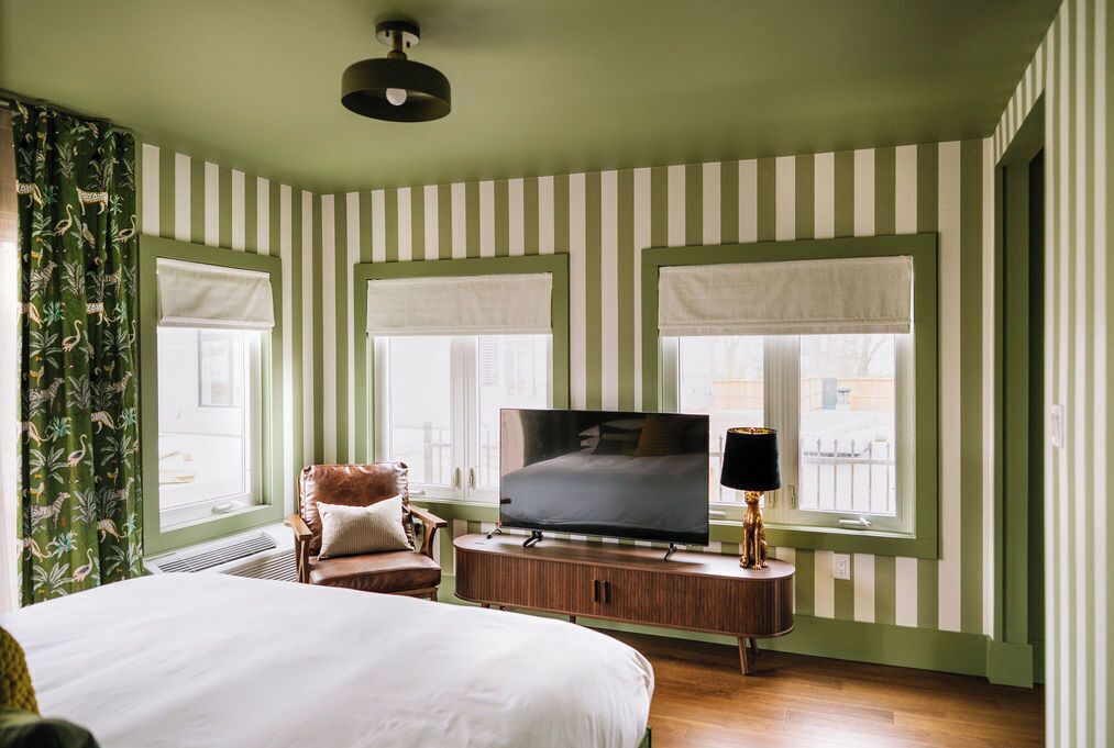 Habitació d'hotel amb llit, televisió, cadira i finestra amb vistes.