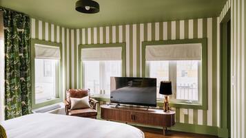A hotel room with a bed, a TV, a chair, and a window with a view.