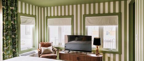 A hotel room with a bed, a TV, a chair, and a window with a view.