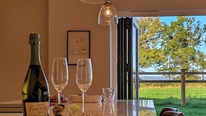 A modern kitchen with a central island, wine bottle, glasses, and a framed picture on the wall. - The Gathering Barn | Hot Tub | Sleeps 12 | Luxury Countryside Views | (Hereford)