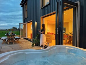 Une maison moderne dotée d’un jacuzzi, d’un coin repas et d’une personne qui se dirige vers l’entrée.