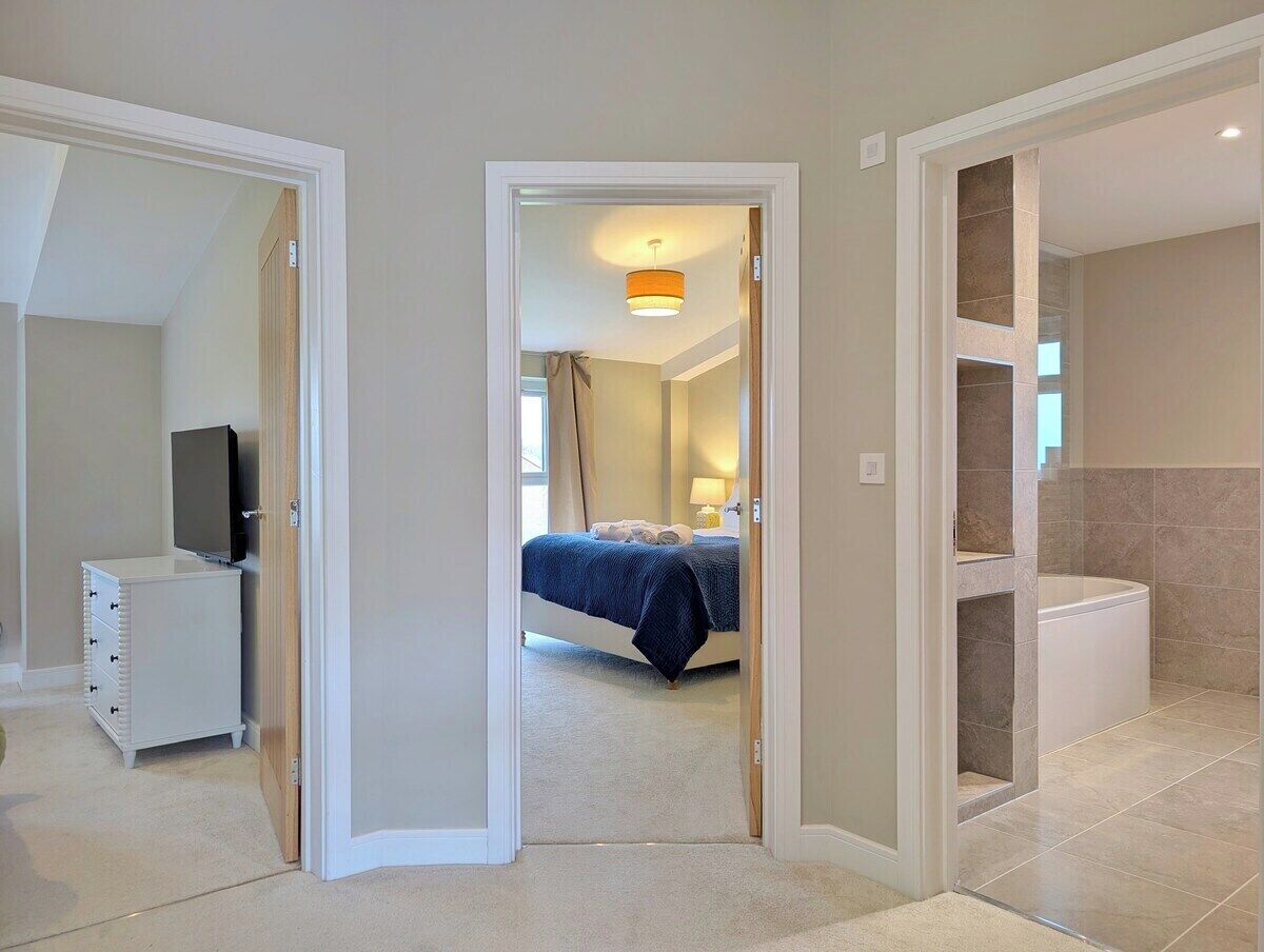 Una habitación de hotel con cama, televisión, cómoda y baño con bañera.