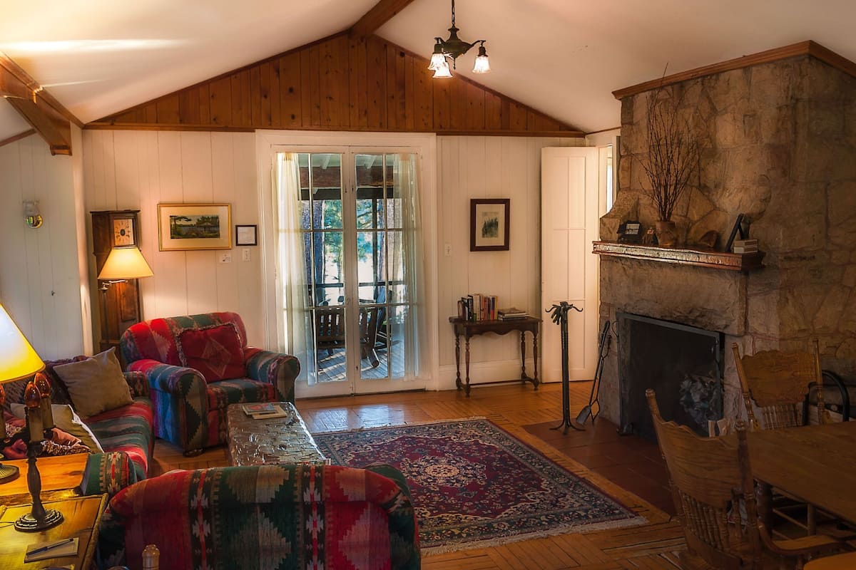 Un salón acogedor con chimenea, techo de madera y un ventanal grande.
