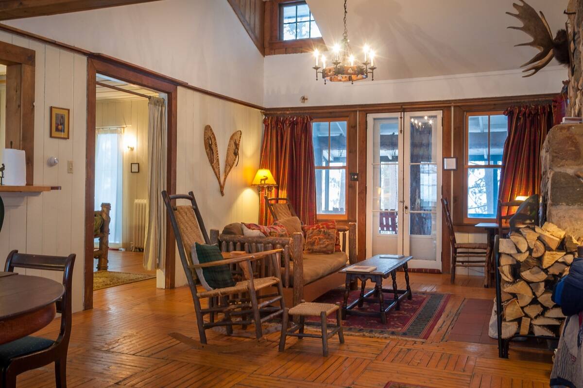 Una sala de estar acogedora con muebles de madera, chimenea y candelabro.