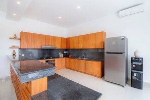 Eine moderne Küche mit Holzschränken, einer Granitabdeckung, Edelstahlgeräten und einem eingebauten Ofen.