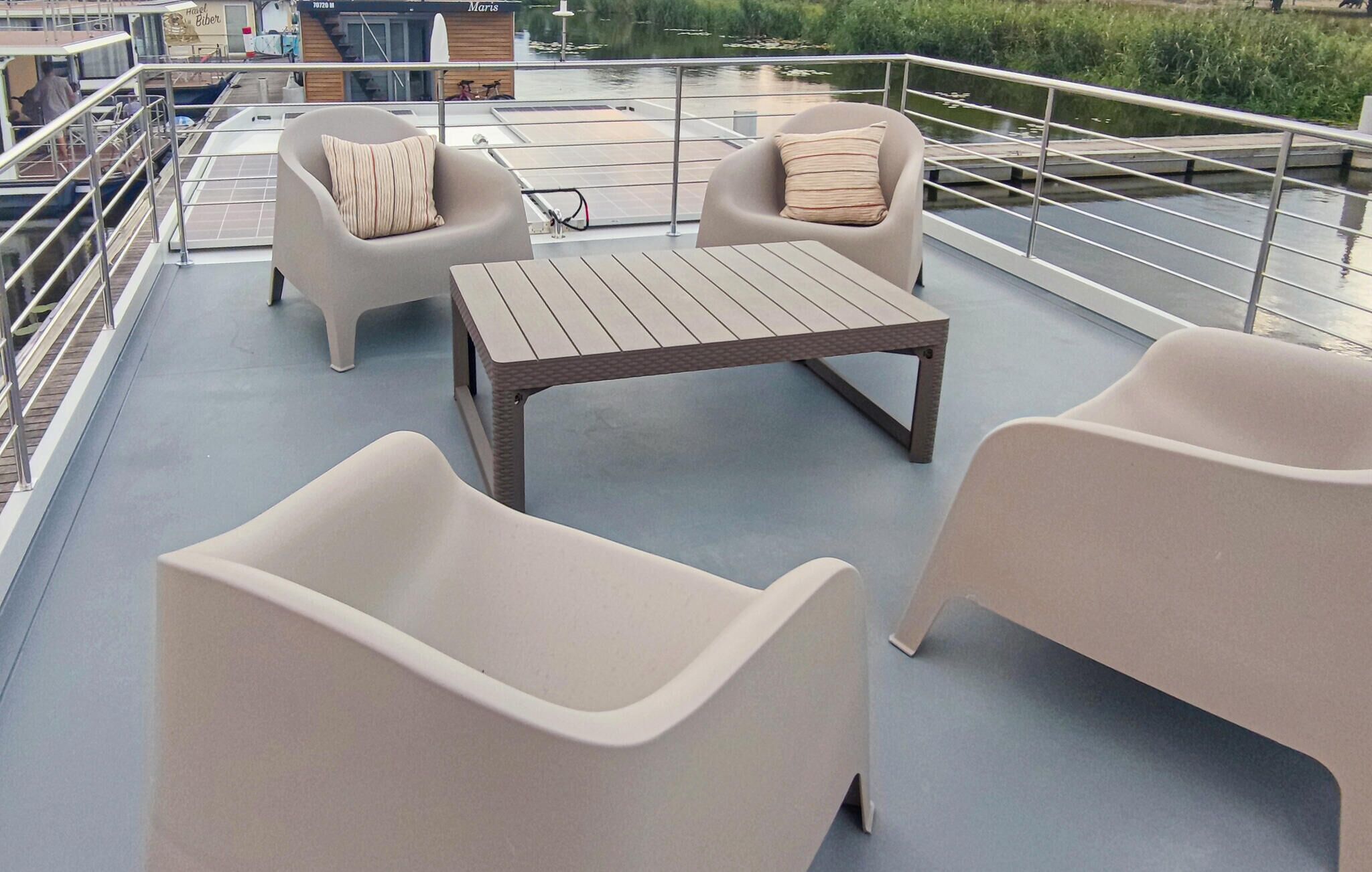 Een terras op het dak met twee banken en een tafel, omgeven door een metalen reling.