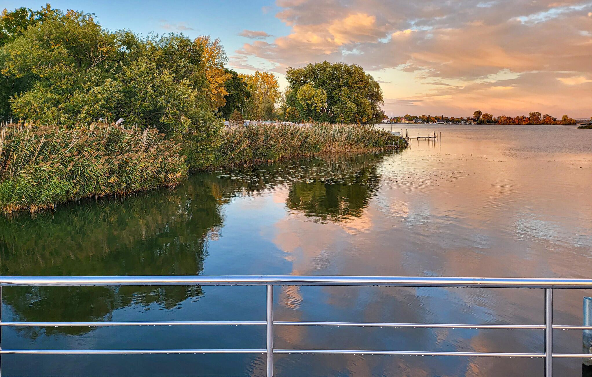Une rivière paisible, bordée d’arbres, avec un quai.