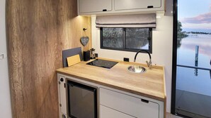 Una kitchenette compacta con estufa integrada, un lavamanos y ventana con vista al agua.