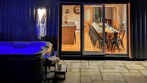 Una casa moderna con jacuzzi, un comedor con una mesa grande y sillas, y una cocina visible a través de las puertas de cristal.