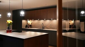 Una cocina moderna con armarios de madera oscura, una isla central con un lavamanos e iluminación colgante.