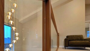 Un interior moderno con una escalera de madera, un sofá verde y una lámpara colgante.