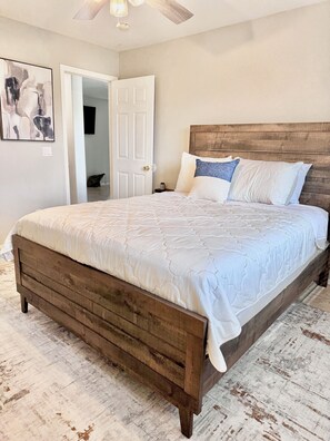 Ein Schlafzimmer mit einem Bettgestell aus Holz, einer weißen Bettdecke und einem Kopfteil.