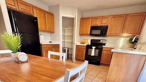 A kitchen with wooden cabinets, a black refrigerator, a microwave, and a stove. - new listing (Phoenix)