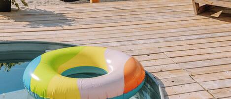 A pool with a floating ring, wooden deck, and a sign indicating the pool's depth.