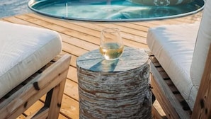 A pool area with lounge chairs and a table, surrounded by a wooden deck. - Penny's Motel & Apres (Thornbury)