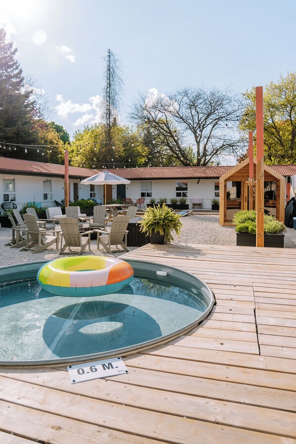 Ein Pool mit einem Schwimmreifen, Sitzgelegenheiten im Freien und einer kleinen Holzkonstruktion.
