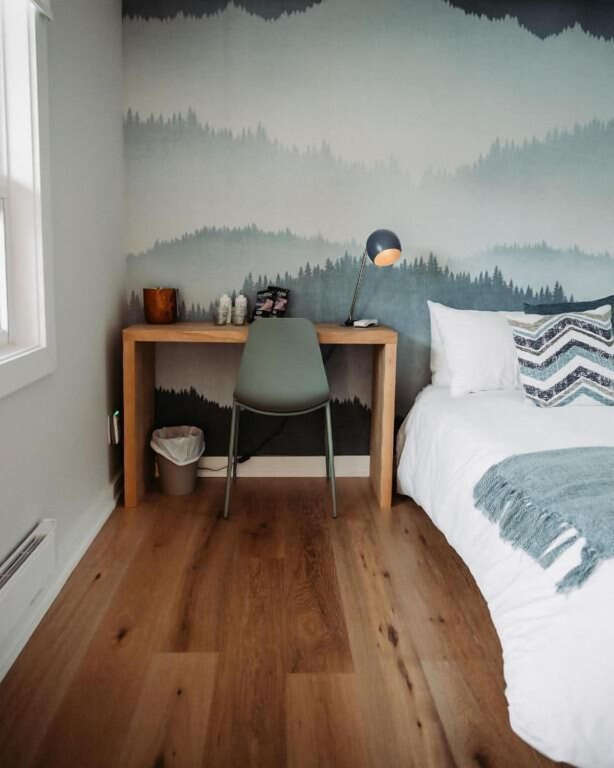 A bedroom with a bed, a desk, and a chair.