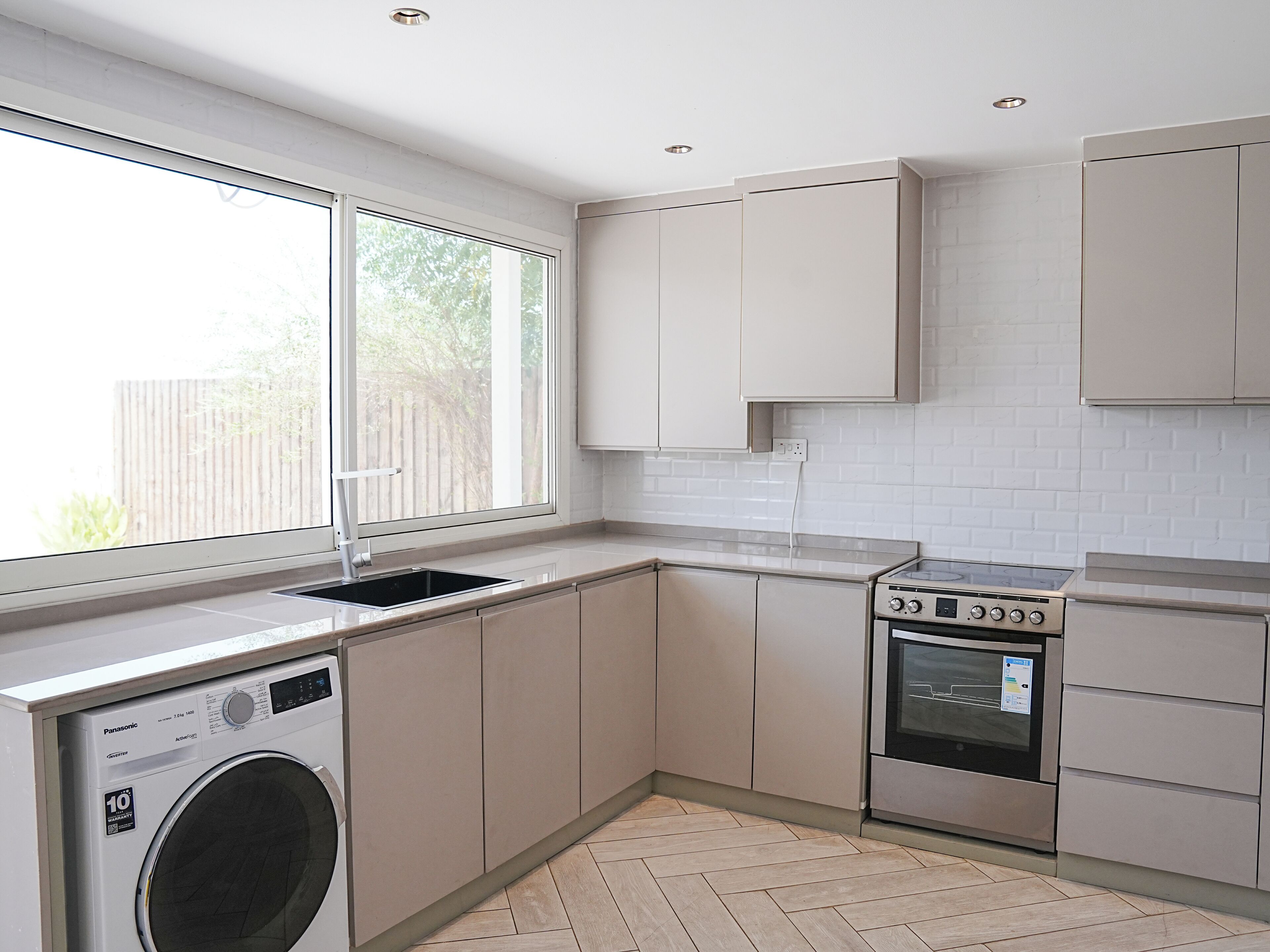 A modern kitchen with a washing machine, oven, and cabinets.