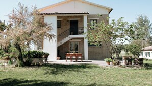 Una casa de dos pisos con un balcón, una escalera y un porche delantero con un banco.
