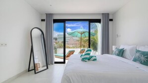 Een moderne hotelkamer met een groot bed, uitzicht op het buitengebied en een schuifdeur naar een balkon met een groene parasol.