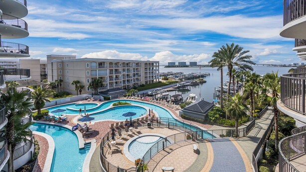 Ein Resort mit einem großen, gewundenen Schwimmbad, einem Hafen und Blick auf das Wasser.