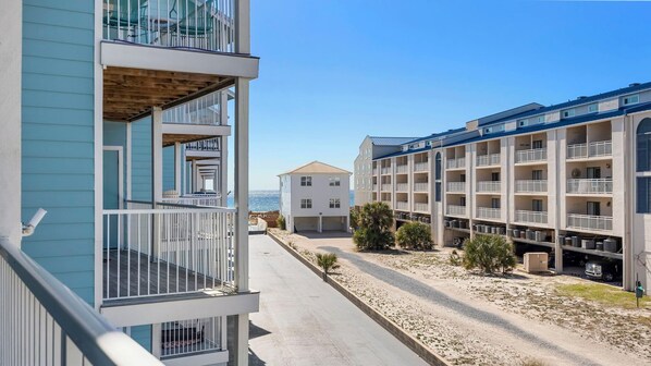 A coastal hotel with multiple balconies, a parking area, and a view of the ocean. - Salt and Light at Romar Beach 213 (Orange Beach)