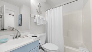 A modern bathroom with a white sink, a mirror, a toilet, and a shower area. - Salt and Light at Romar Beach 213 (Orange Beach)