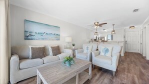 Un salon avec un canapé, des fauteuils, une table basse et un tableau au mur.
