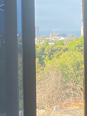 A view through a window with a cityscape in the background, including buildings and greenery. - LIVE SANTA MARTA (Bello Horizonte)