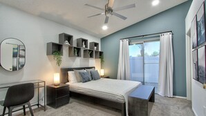Une chambre moderne comprenant un lit, des tables de chevet, un bureau, une chaise, un ventilateur de plafond et une fenêtre avec des rideaux.