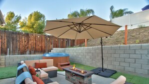 Une terrasse extérieure dotée d’un foyer, d’un espace salon et d’un grand parasol.