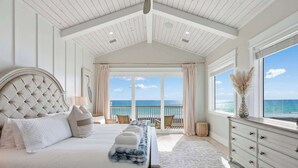 Una camera da letto con un letto grande, una cassettiera e vista sull'oceano.