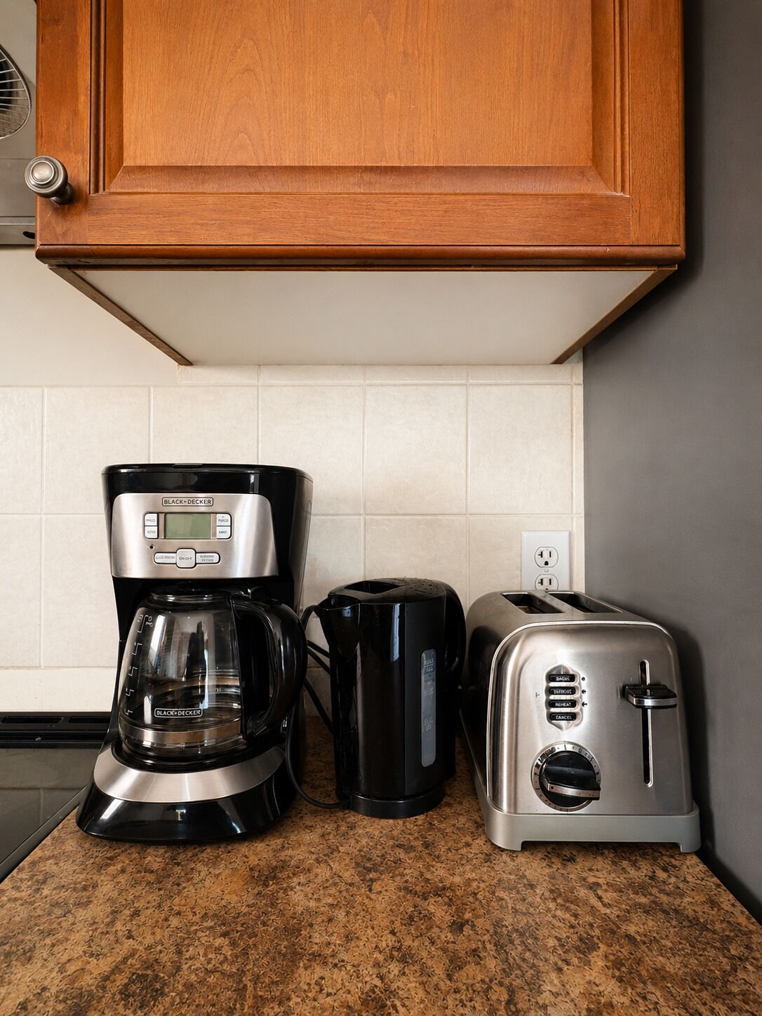 Een keuken met een koffiezetapparaat, broodrooster en een kast boven het aanrecht.