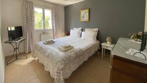 Un dormitorio con una cama, un escritorio, una silla, una ventana y un cuadro en la pared.
