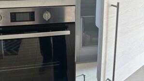 Una cocina con horno de acero inoxidable, microondas y refrigerador integrado.