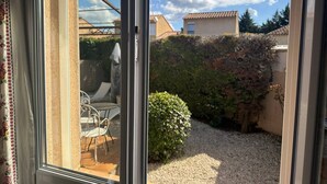 Un patio con mesa y sillas, una zona de grava y un seto.