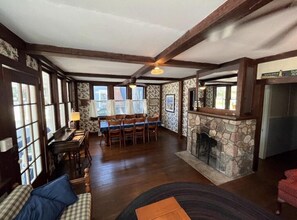 A spacious living room with a fireplace, a dining area, and large windows. - Charming Cottage in Lakeside (Lakeside)