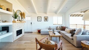 Amplia sala de estar con chimenea, un conjunto de sofás, una silla de madera y una mesa de centro.