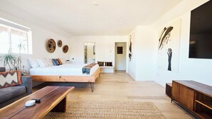 Un dormitorio moderno con una cama grande, un banco de madera y un televisor.