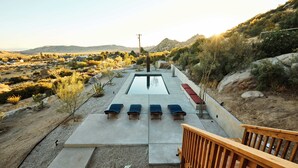 Un área de piscina con sillones de descanso y una terraza de madera.