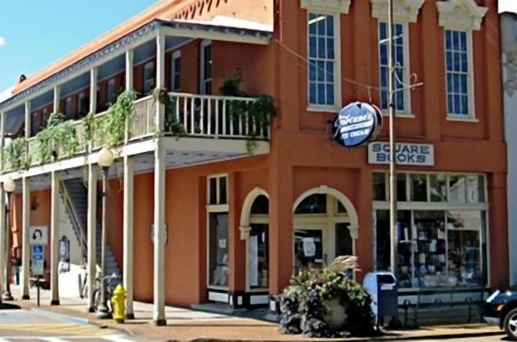 A two-story building with a balcony, a storefront, and a fire hydrant.