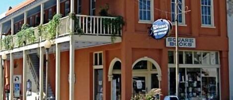 A two-story building with a balcony, a storefront, and a fire hydrant.