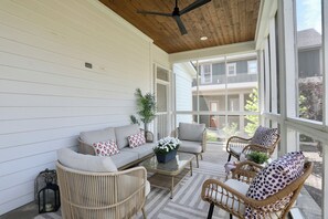A covered outdoor seating area with a sofa, chairs, and a table, overlooking a residential building. - "Sippin on Savannah Square" by OVR (Oxford)