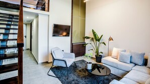 A modern living room with a sofa, a coffee table, a TV, and a staircase. - THE LYNX KONITSA (Konitsa)