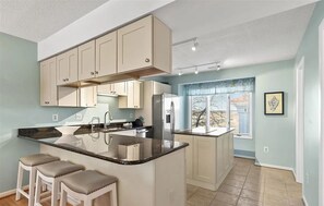 A modern kitchen with a central island, built-in appliances, and a large window providing natural light. - Pebble Paradise - Easy Walk to the Beach & Town (Bethany Beach)